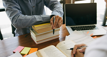 A set of hands showing business shirt cuffs holds TPA insurance paperwork as another hand points to something on the paper. 