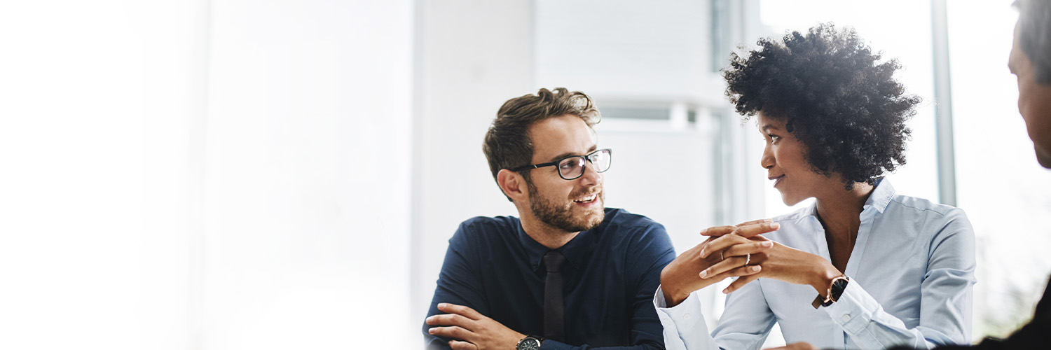 Two women and two men sitting next to each other smiling and discussing self-funding employee benefits. 